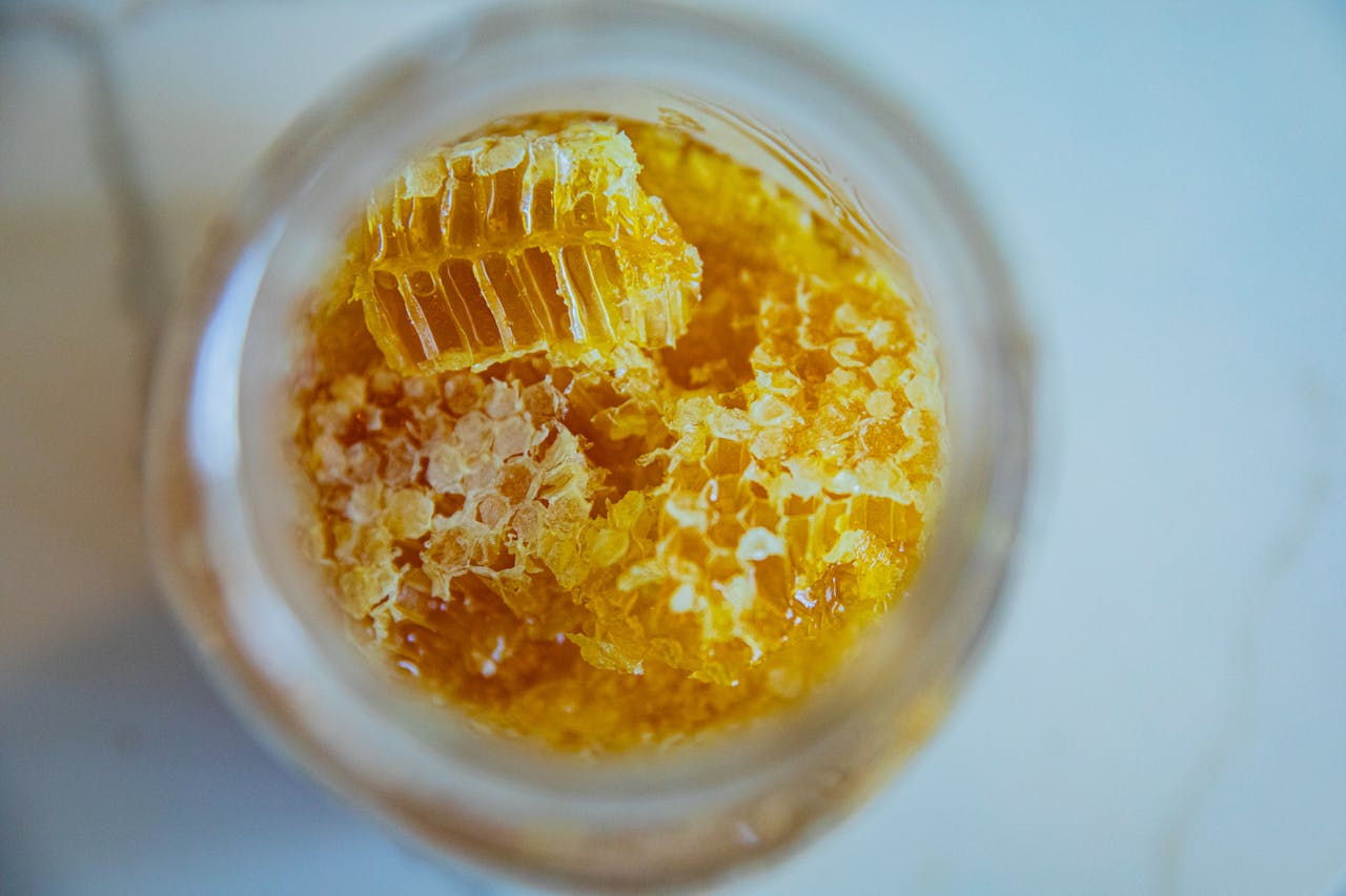 Close-up view of fresh honeycomb pieces in a jar, showcasing natural sweetness and texture.